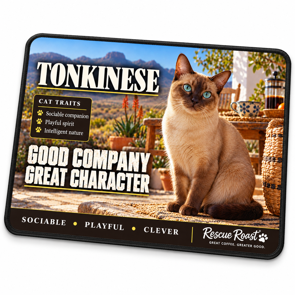 Rescue Roast Tonkinese mousepad: An aqua-eyed Tonkinese sits on a woven cushion on a rustic stoep beside a coffee cup and cafetière, with mountains beyond. Printed slogan: Good Company, Great Character.